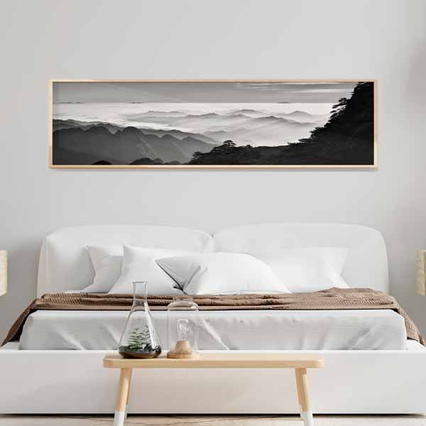 Quadro horizontal de montanhas envoltas em nevoeiro, com picos distantes, árvores escuras e camadas de névoa em branco, cinzento e preto, em estilo natureza e paisagem. Disponível em kudeko.com
