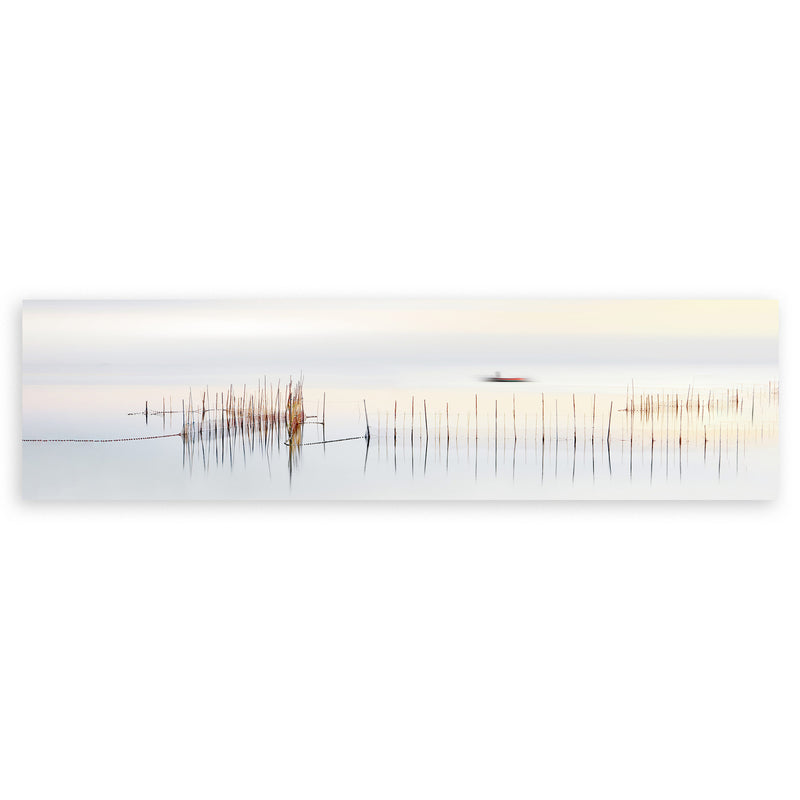 Cuadro horizontal de barca lejana sobre agua tranquila con cañas finas, tonos blanco, beige, gris y marrón, de estilo fotográfico. Disponible en kudeko.com
