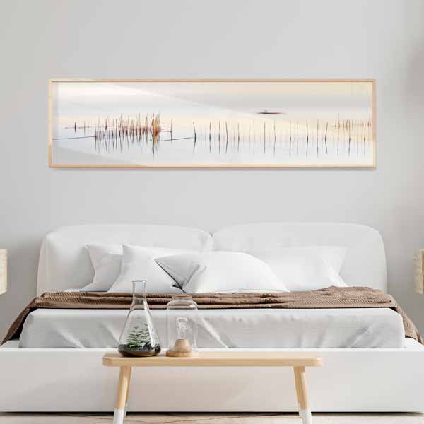 Quadro horizontal com barco ao longe sobre água tranquila, caniços finos em primeiro plano, tons de branco, bege, cinzento e castanho, estilo fotográfico suave e luminoso. Disponível em kudeko.com
