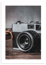 Tableau avec appareil photo rétro au premier plan sur surface en bois, tons gris, noirs et bruns, style vintage élégant et nostalgique. Disponible sur kudeko.com