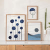 Conjunto de três quadros com formas circulares azuis, linhas finas pretas, semicírculo geométrico e paisagem minimalista em azul, cinzento e preto, num estilo abstrato depurado. Disponível em kudeko.com
