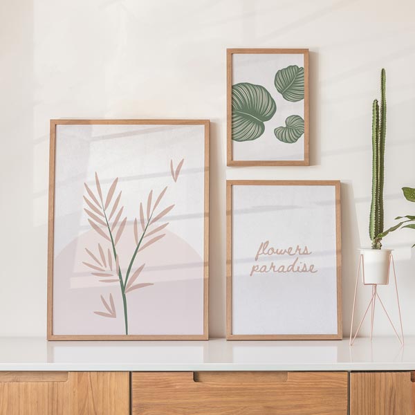 Set aus drei Wandbildern mit tropischen Blättern in Salbeigrün, botanischem Zweig in Puderrosa, Schriftzug flowers paradise, weißem Hintergrund und minimalistischem Stil. Erhältlich auf kudeko.com